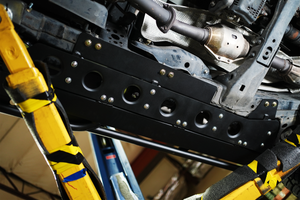 Close-up of black Metal Tech 4x4 rock sliders installed on the underside of a Lexus LX570 frame.