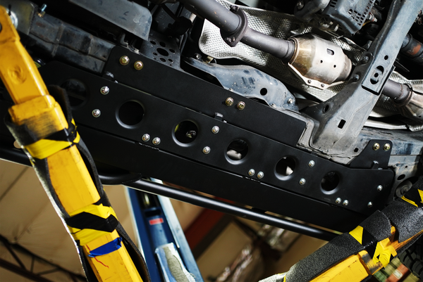 Close-up of black Metal Tech 4x4 rock sliders installed on the underside of a Lexus LX570 frame.