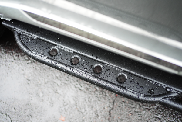 Close-up of black Metal Tech 4x4 rock slider with water droplets installed on Lexus LX570 side step.