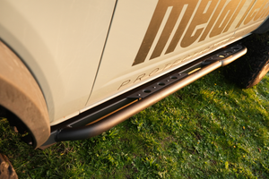 Close-up of black Sidewinder rock sliders installed on the side of a 2021 Bronco 4-door on grass.