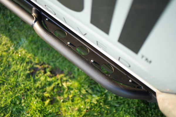 Close-up of black powder-coated Sidewinder rock slider installed on 2021 Bronco 4-door, showing mounting bolts and welds.