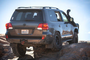 Rear side view of a Toyota Land Cruiser 200 Series with Metal Tech rock sliders, off-road on rocky terrain.
