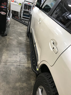 Black Metal Tech 200 Series rock sliders installed on white 2008-2021 Toyota Land Cruiser side view in garage.