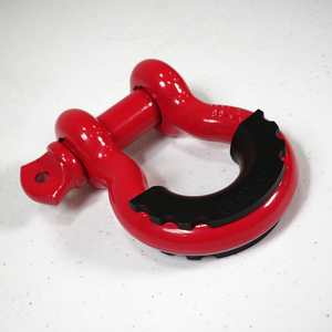 Close-up of a red powder-coated metal shackle with a black protective cover on a white surface.