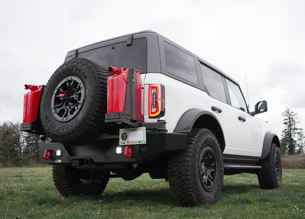 White Bronco 6G with Metal Tech 4x4 rear Aces High bumper, dual red jerry cans, and spare tire mounted outdoors.