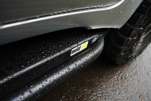 Close-up of wet black Metal Tech 4x4 rock slider installed on Lexus LX570 side near rear tire.