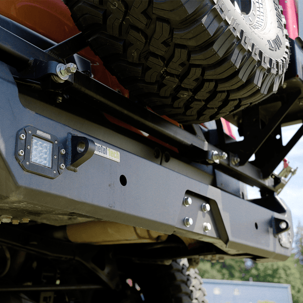Close-up of Metal Tech Red Eye II full shell rear swing-out bumper installed on red FJ Cruiser with spare tire mount.