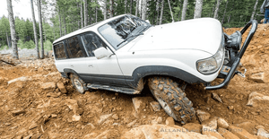 White 80 Series Land Cruiser with Metal Tech 4x4 rock sliders navigating rocky off-road terrain.