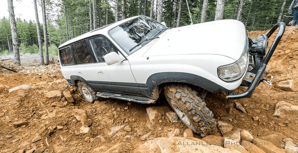 White 80 Series Land Cruiser with Metal Tech 4x4 rock sliders navigating rocky off-road terrain.