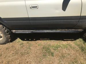 Side view of black Metal Tech 4x4 rock slider installed on white 80 Series Land Cruiser LX450 on dry grass.