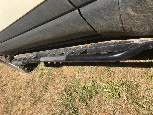Close-up of black metal rock slider installed on side of 80 Series Land Cruiser LX450, showing dirt and wear.