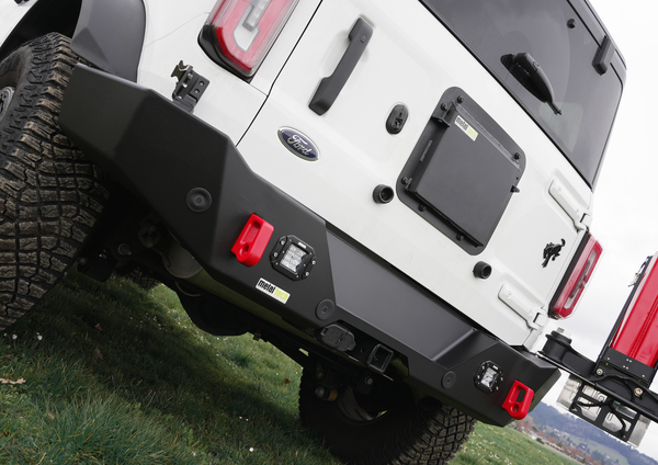 Close-up of black Metal Tech 4x4 Bronco 6G rear Aces High bumper installed on white Ford Bronco with red tow hooks.