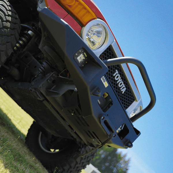 Close-up of black Metal Tech Phantom front bumper installed on red Toyota FJ Cruiser under clear blue sky.