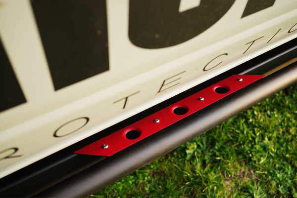 Close-up of red metal plate with holes mounted on black Sidewinder rock slider on 2021 Bronco 4-door.