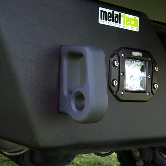 Close-up of black Cerakote-finished aluminum rear bumper pull point mounted next to a square off-road light.