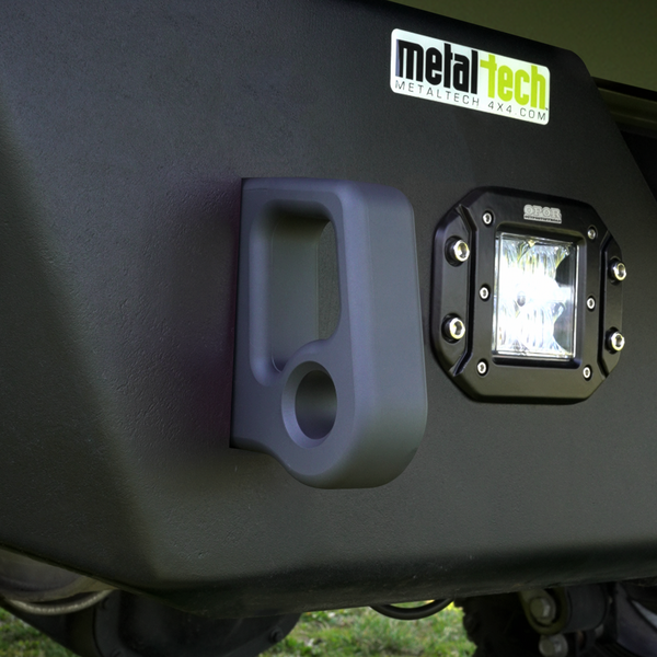 Close-up of black Cerakote-finished aluminum rear bumper pull point mounted next to a square off-road light.