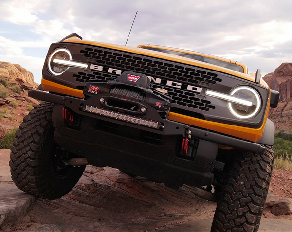Yellow Bronco 6G with Stronghold winch mount and Warn VR Evo winch on rugged off-road terrain.
