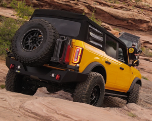 Yellow Bronco 6G with Metal Tech 4x4 rear Aces High bumper driving on rocky terrain.