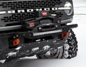 Close-up of Bronco 6G front bumper with Stronghold winch mount and Warn VR EVO winch in snowy terrain.