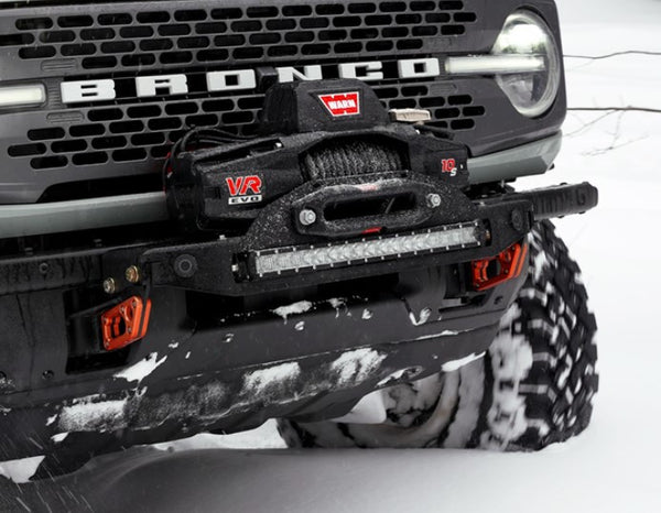 Close-up of Bronco 6G front bumper with Stronghold winch mount and Warn VR EVO winch in snowy terrain.