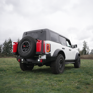White Ford Bronco 6G with Metal Tech 4x4 rear Aces High bumper, dual red fuel cans, and spare tire mounted outdoors.