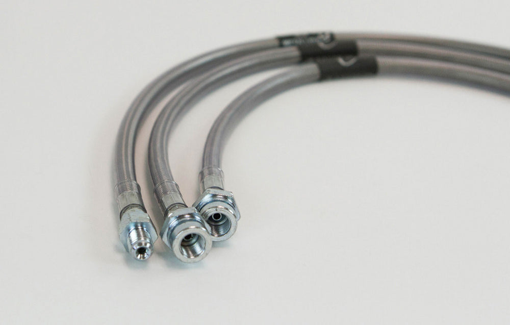 Close-up of three stainless steel extended brake lines with metal fittings for 3 to 6-inch lifted Land Cruiser 80 Series.