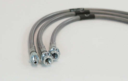 Close-up of three stainless steel extended brake lines with metal fittings for 3 to 6-inch lifted Land Cruiser 80 Series.