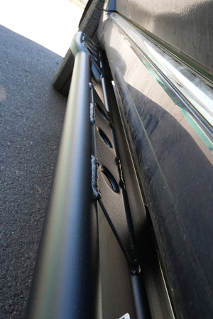 Close-up of black metal rock slider installed on side of 2010-2013 4Runner, showing weld details and mounting points.