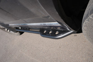 Close-up of black metal rock slider installed on 2010-2013 Toyota 4Runner side near rear tire.