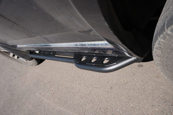 Close-up of black metal rock slider installed on 2010-2013 Toyota 4Runner side near rear tire.