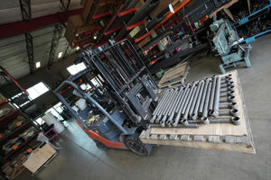Forklift carrying metal offset rear lower links for FJ Cruiser and 4Runner on a wooden pallet in a warehouse.