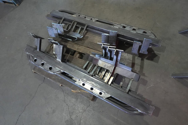 Unpainted metal rock sliders for 80 Series Land Cruiser LX450, shown from above on a concrete floor.