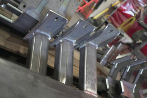 Close-up of welded metal brackets for 80 Series Land Cruiser LX450 rock sliders in workshop setting.