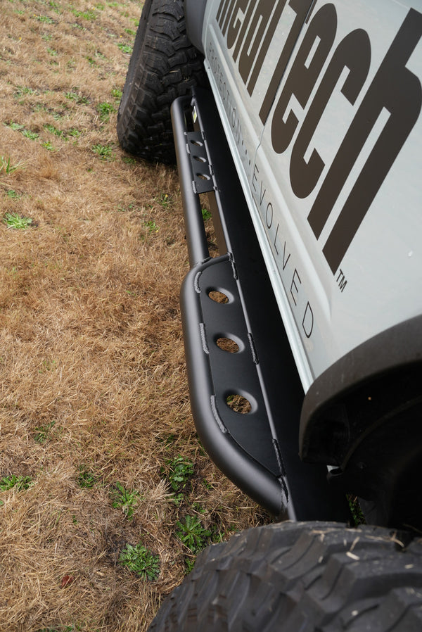 Close-up side view of black Bronco 6G rear Aces High bumper installed on white off-road vehicle.