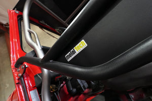 Close-up of black Metal Tech tube door installed on red FJ45 Land Cruiser showing frame and logo sticker.