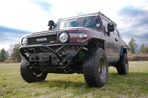 Front view of a Toyota FJ Cruiser with a black Metal Tech front tube bumper installed on grassy terrain.