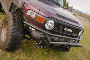 Close-up of a black Metal Tech front tube bumper installed on a maroon Toyota FJ Cruiser outdoors.