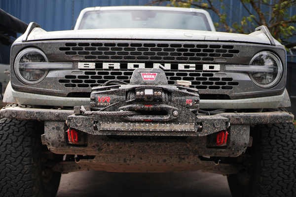 Front view of a muddy Ford Bronco 6G with a Warn VR EVO winch mounted on the Stronghold winch mount.