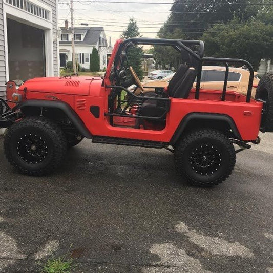 Side view of red Toyota FJ40 Land Cruiser with installed black Jackson roll cage and off-road tires.