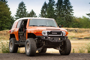 Orange Toyota FJ Cruiser with Metal Tech Phantom front bumper installed, off-road tires, and open driver door.