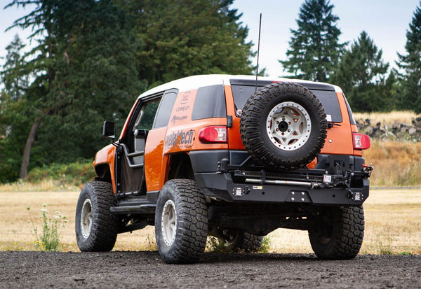Rear view of orange FJ Cruiser with Metal Tech Red Eye II full shell rear swing-out bumper and spare tire mounted.