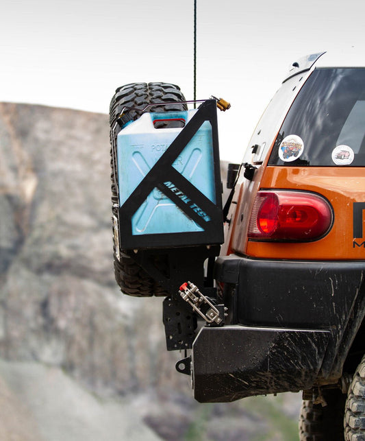 Rear view of orange FJ Cruiser with Metal Tech Red Eye II full shell swing-out bumper and mounted spare tire and jerry can.