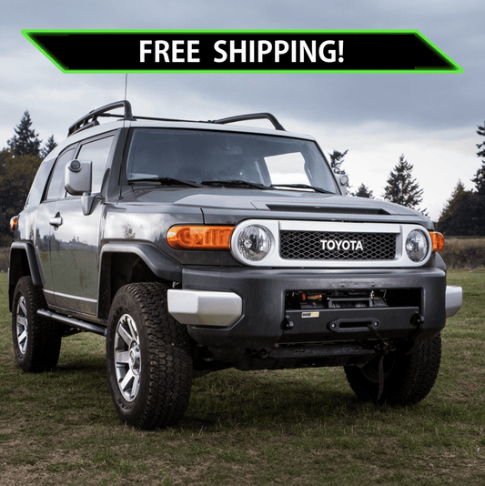 Toyota FJ Cruiser with Metal Tech Stronghold winch bumper installed on grassy field under cloudy sky.