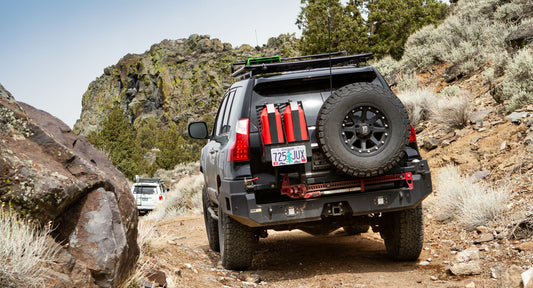 Rear view of a Lexus GX460 with Metal Tech Lancer rear swing-out bumper and off-road gear on a dirt trail.