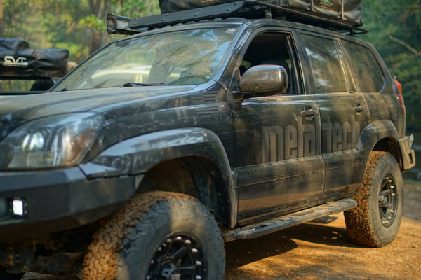 Side view of a muddy black Lexus GX470 with Metal Tech 4x4 rock sliders installed for off-road protection.