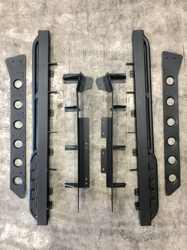 Flat lay of black metal rock sliders and mounting brackets for Lexus LX570 on concrete floor.