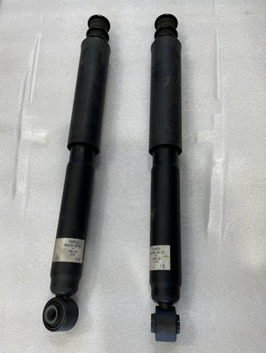 Pair of black stock rear shocks for 5th gen Toyota 4Runner with mounting bushings and labels visible.