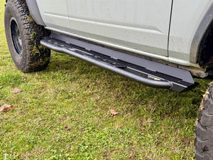 Close-up of black Metal Tech rock slider installed on the side of a 2021 Ford Bronco 4-door on grass.