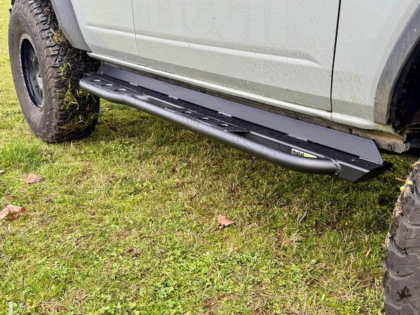 Close-up of black Metal Tech rock slider installed on the side of a 2021 Ford Bronco 4-door on grass.