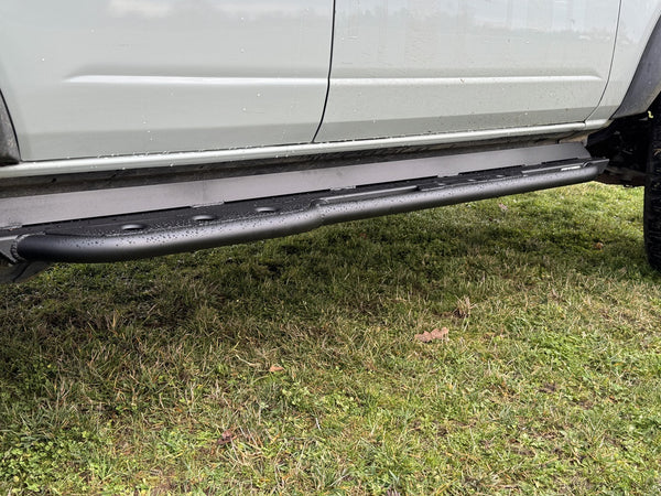Close-up of black metal rock slider installed on the side of a white 2021 Ford Bronco 4-door.